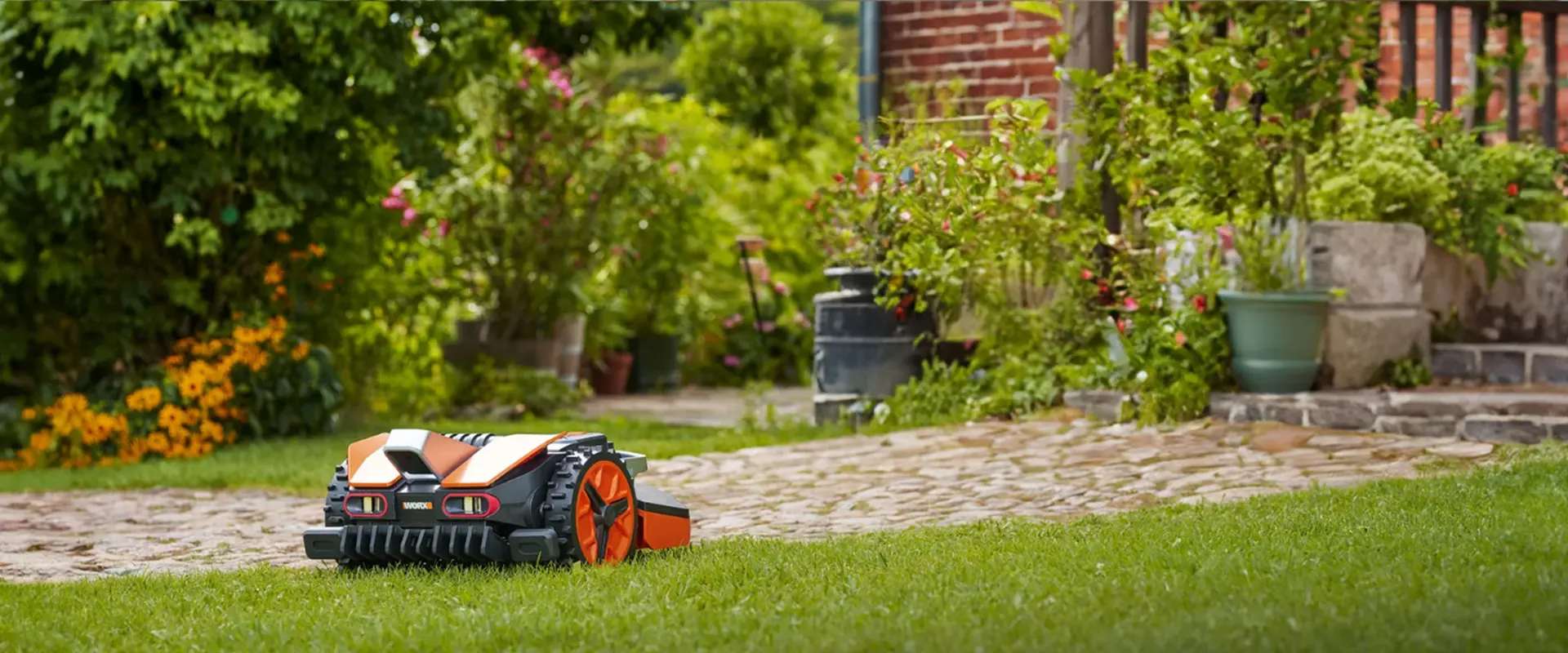 WORX Landroid robotic lawn mower working while a family enjoys a braai